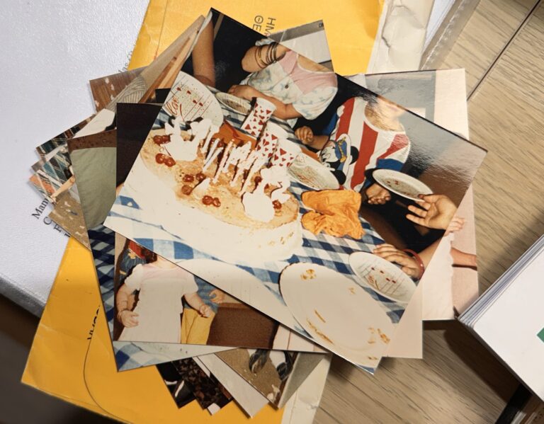 a collection of photographs depicting a child's birthday party and resting on top of a yellow photographic envelope.